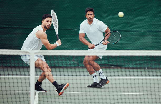 два этнических теннисиста держат ракетки и играют на корте. серьезная, сфокусированная команда спортсменов вместе во время матча. проведен - two pairs стоковые фото и изображения