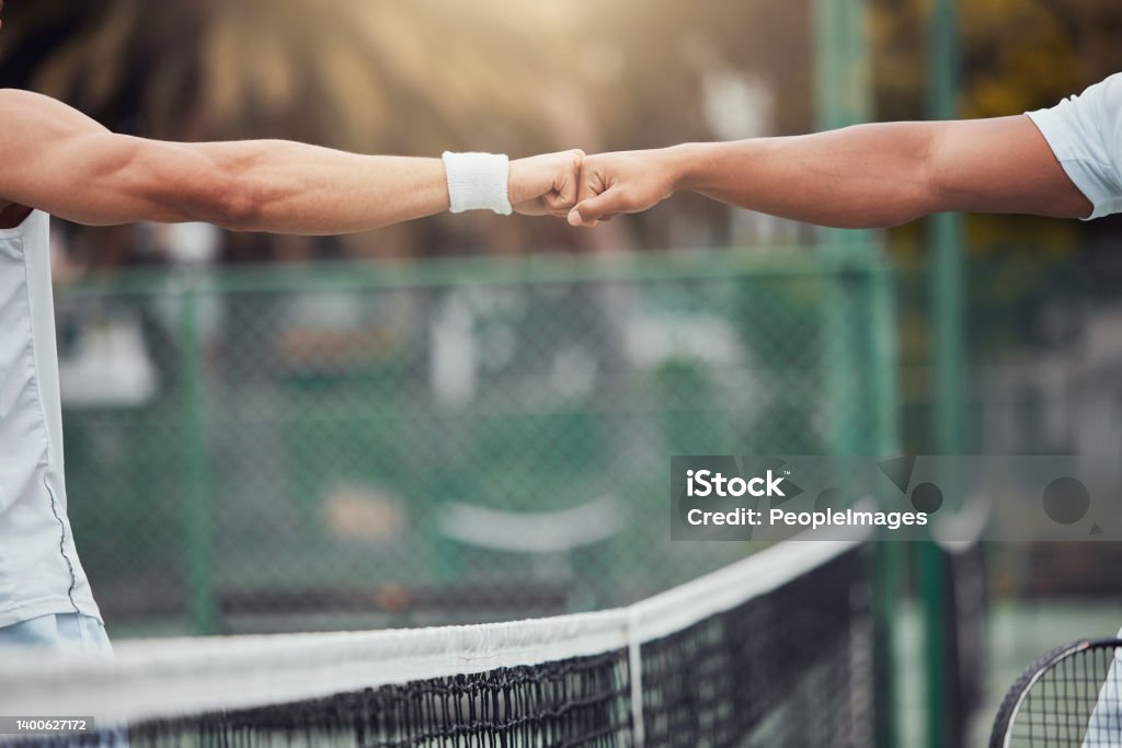 Two unknown ethnic tennis players giving fistbump with fist before playing court game. Fit athletes team standing and using hand gesture for good luck. Play competitive sports match for health fitness Friendship Stock Photo