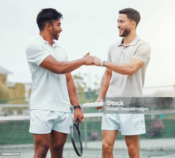 Two Smiling Ethnic Tennis Players Giving Fistbump With Fist Before Playing Court Game Fit Athletes Team Standing And Using Hand Gesture For Good Luck Play Competitive Sports Match For Health Fitness Stock Photo - Download Image Now