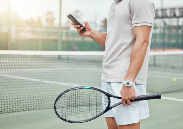 istock Unknown mixed race tennis player using cellphone to text during break in game on court. Hispanic fit athlete browsing internet and networking on phone after match. Active healthy man in sports club 1400627214