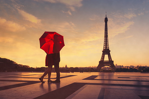 silhouette of lovers kissing under a red umbrella on a blurred background