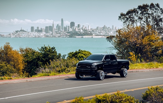 San Fran, CA, USA\n5/1/2022\nLifted Black Dodge Ram Truck with larger wheels parked on the side of the road with San Francisco in the background