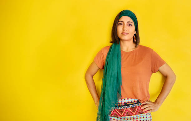 istock Stylish young woman standing against a bright yellow background 1400634986