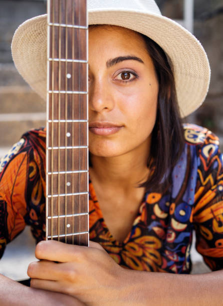 istock Young female musician sitting with a guitar outside on steps 1400635175