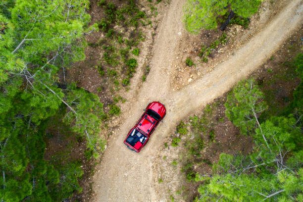 Top view photo of Red pick up lost in the forest road stock photo