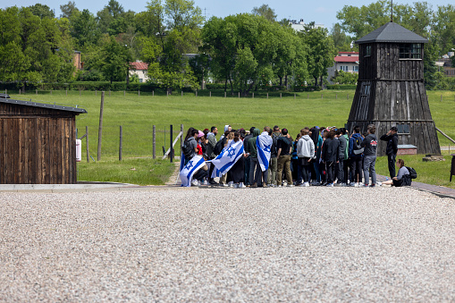 Majdanek; Lublin; Poland - May 25, 2022: A group of Jewish tourists in the Majdanek Nazi concentration and extermination camp ( Konzentrationslager Lublin), view of guard tower and wooden barrack