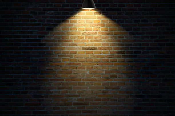 Photo of Dark brick wall illuminated by a lamp