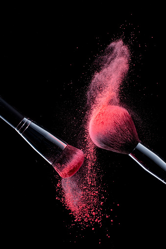Makeup Brushes with pink color powder on black background