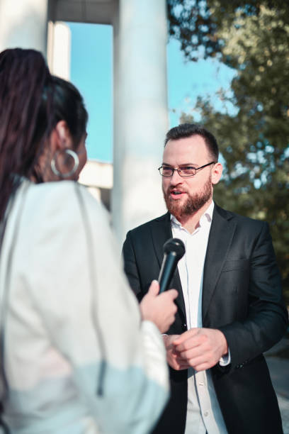 istock Male Politician Explaining Program During Live Broadcast From City Park 1400639471