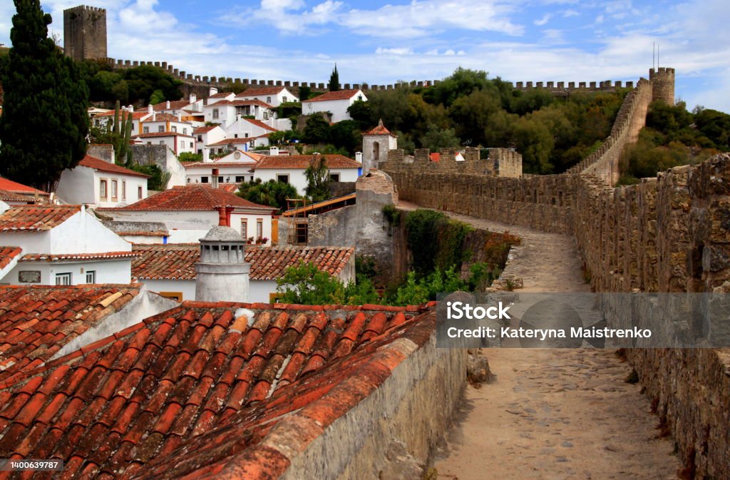 View of the historic part of the town of Obidos, Portugal White houses with red roofs and exotic trees surrounded by the walls of the Castle of Obidos Obidos Stock Photo