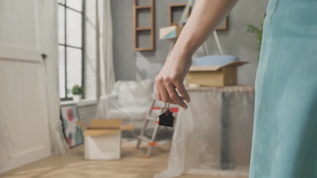 woman moving into new house holding home key hand close up
