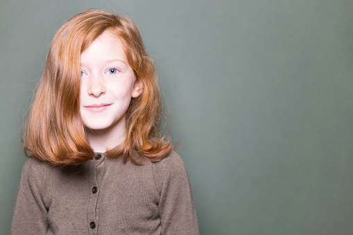 Portrait of a pretty 7-year-old Caucasian girl with ginger hair and blue eyes.