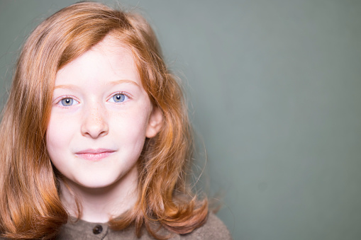 Portrait of a pretty 7-year-old Caucasian girl with ginger hair and blue eyes.
