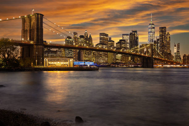 Brooklyn Bridge and New York City Skyline with Manhattan Financial District and World Trade Center at Orange Yellow Sunset. stock photo