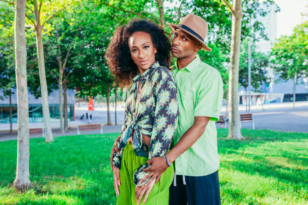 Portrait of multiracial couple enjoying and posing at park. Emotional millennial multiracial afro couple having a date at sunset. Looking at camera.
