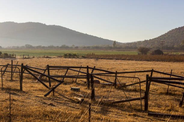 Early morning view over a farm in Rural Free State, South Africa, with a broken Fence in the foreground and the hills of the Vredefort Dome in the Background stock photo