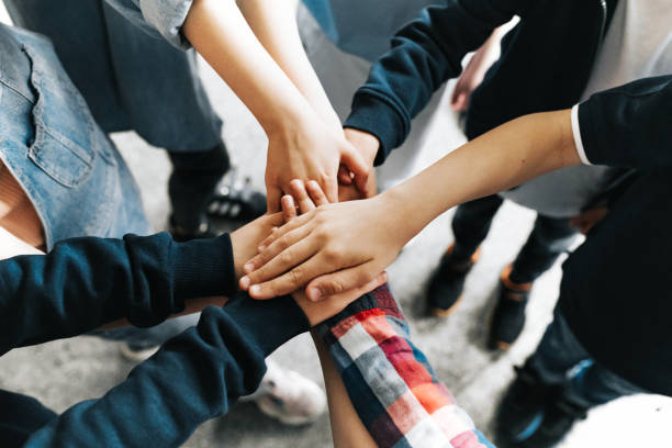 istock group of elementary school children putting hand in a huddle 1400648224