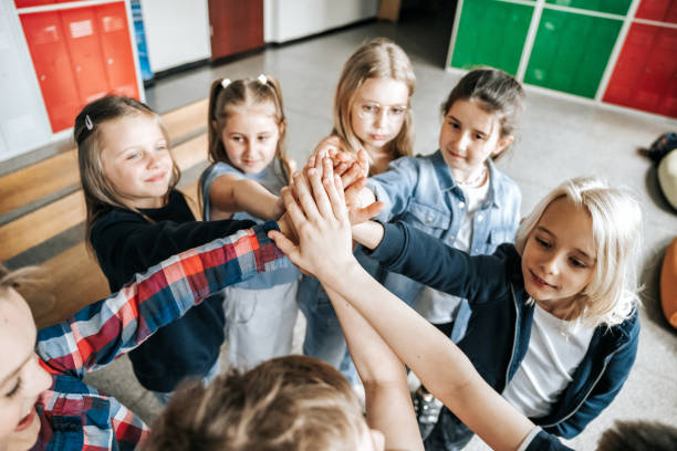 istock group of elementary school children raising up hands together 1400648392