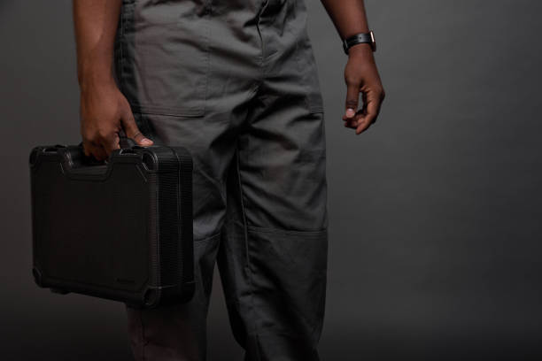black guy with a watch on his arm carries a heavy suitcase with wrenches - thirty pieces of silver imagens e fotografias de stock