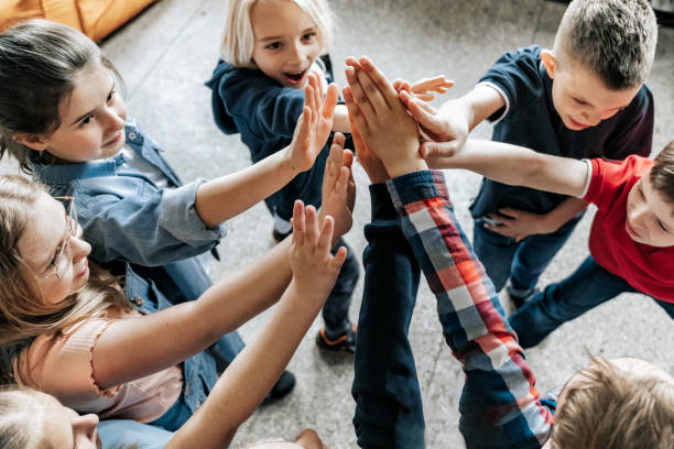 istock group of elementary school children raising up hands together 1400648607