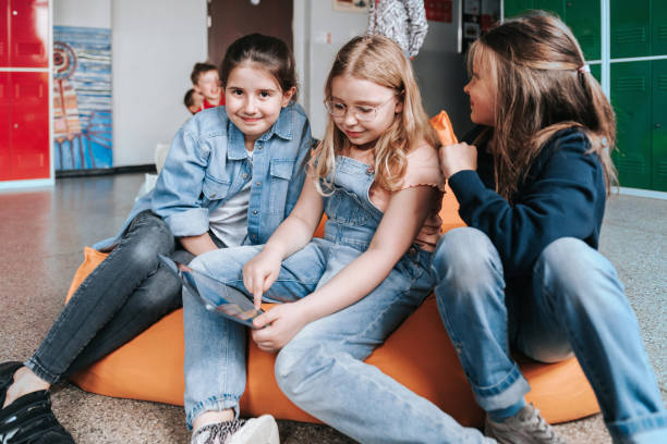 istock three school girls on bean bag and looking on tablet together 1400648767