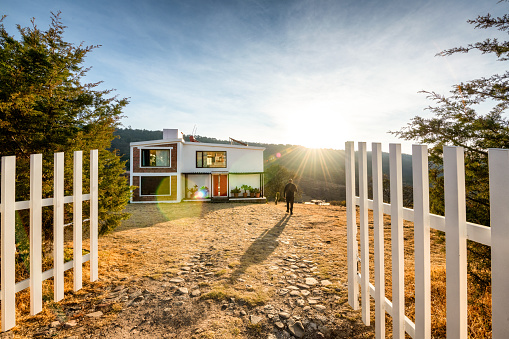 Person walking towards a sustainable off the grid house at sunset