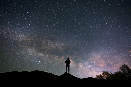 Silhouette traveler on the hill in starry night sky.  Bright milky way galaxy behind him.