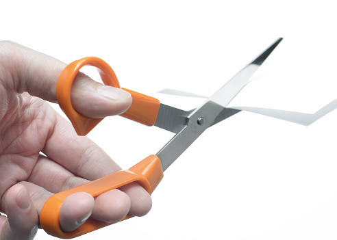 Closeup of a man's hand using scissors against a white background.