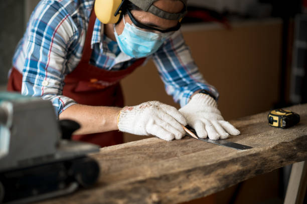 istock A young Asian carpenter with a brown apron uses a wood sander and tape measure while working on a plank. Carpenter concept working in a wood factory. Selective focus. 1400653656