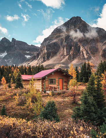 Wooden hut with rocky mountains in autumn forest on national park at Assiniboine, BC, Canada