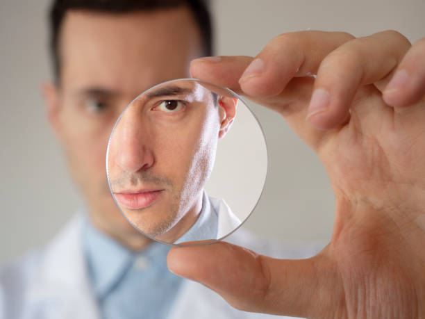Eye care professional Optometrist doctor man holding a glass lens inside laboratory stock photo
