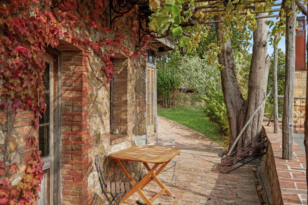 Wooden table and empty metallic chair outside detached brick house during autumn season