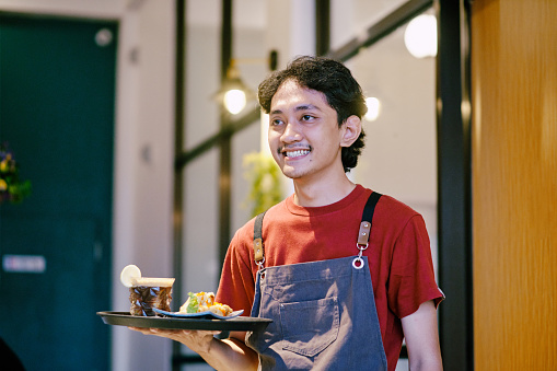 Young men waiter smiling while serving food