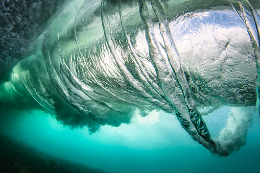 View beneath a breaking wave in the ocean as air spirals into veins