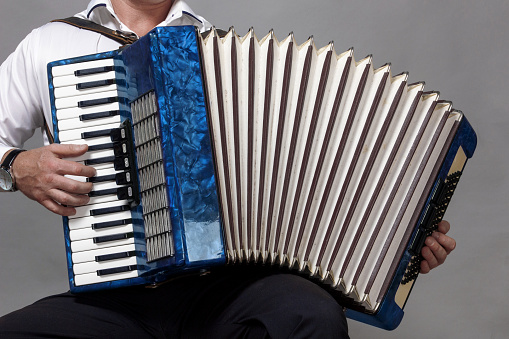 blue accordion, played by a man, in the frame only his hands