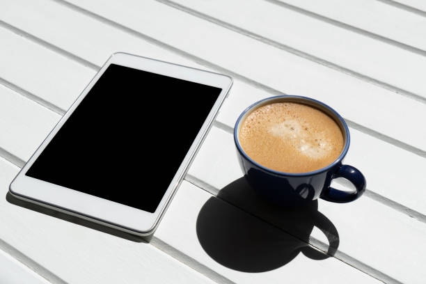 cup of coffee with digital tablet on wooden table
