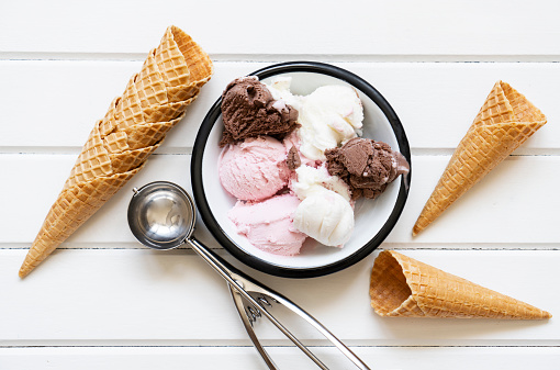 Chocolate, strawberry and vanilla ice cream in a bowl on wooden table