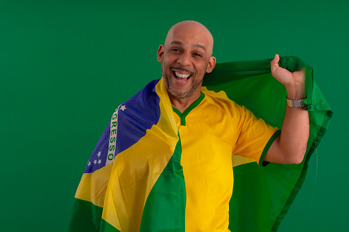 Afro Brazilian man, supporter of the Brazilian football team, with the flag of Brazil and with facial expressions.