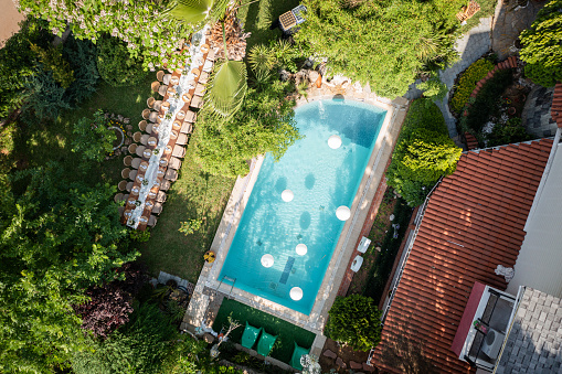 Aerial view of wedding reception and large dining table in garden of modern house with poolside lounge