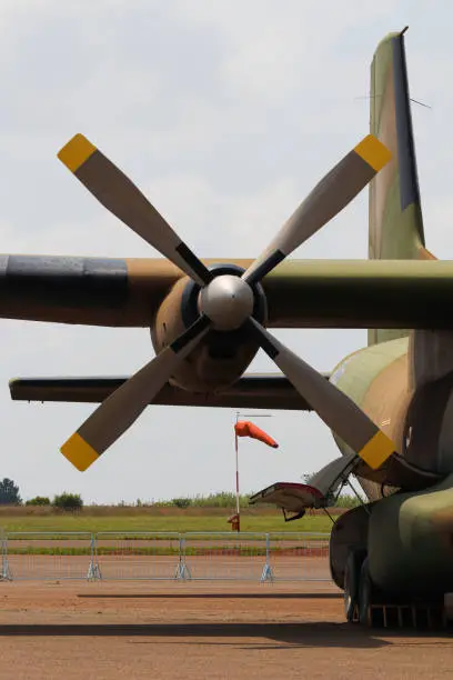 Military C-160 transport aircraft propeller engine close-up with airport wind sock, South Africa