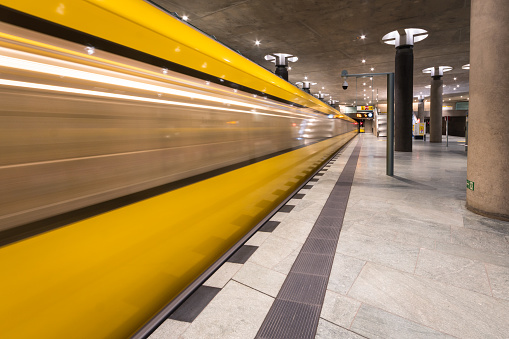 A yellow colored subway driving in to the subway station in Berlin, Germany.