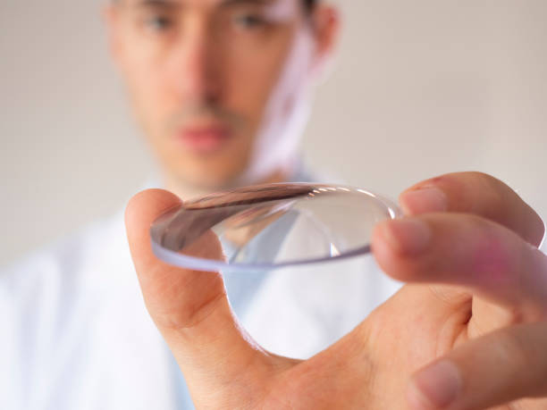 Oculist holds a lens in his hand. Eyewear lens. stock photo