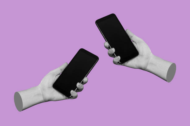 istock Two hands holding mobile phones with black screens, empty copy space for design on lilac background 1400679508