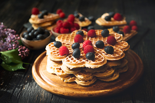 Heart shape Waffles with berry fruits on dark background