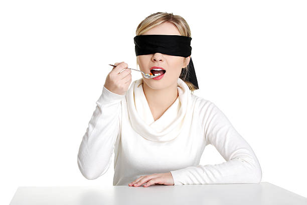 Blindfold woman eating pills stock photo