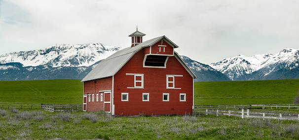 Snow Capped mountains are background to old red barn in eastern Oregon near Joseph, Oregon