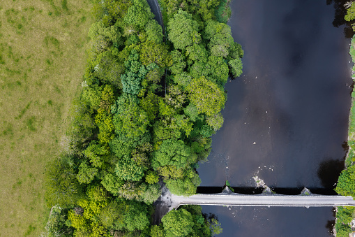 Aerial view from a drone of a river with an old stone built bridge in rural Scotland