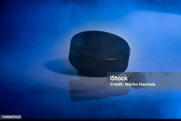 Closeup Of A Rubbery Ice Hockey Puck Against A Blue Smoky Background Stock Photo - Download Image Now