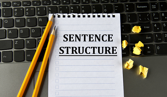 SENTENCE STRUCTURE - words in a white notepad on the background of a laptop with pencils. Business concept