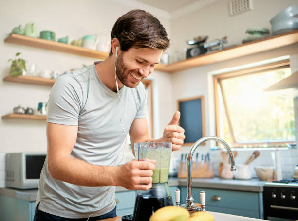 istock One fit young caucasian man using blender to make healthy green detox smoothie while wearing earphones in kitchen at home. Guy having fresh fruit juice to cleanse and provide energy for training. Wholesome drink with vitamins and nutrients 1400692910